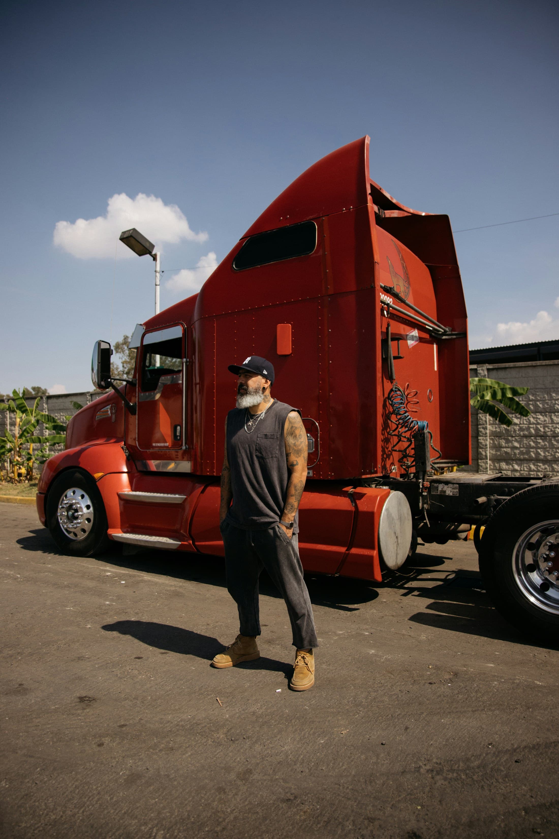A professional truck driver standing beside his red semi-truck